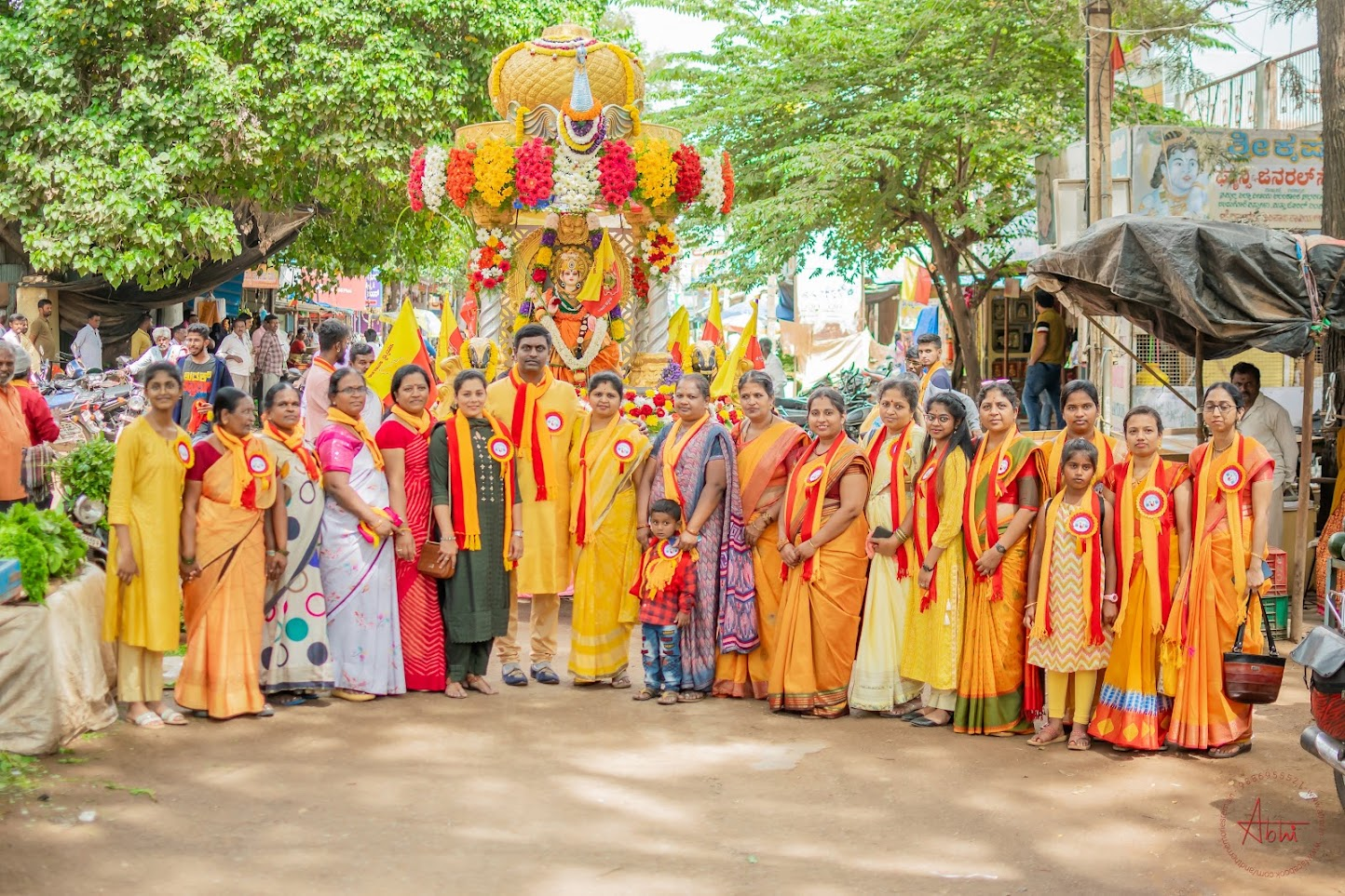 Women in saffron saris before a decorated festival float during the Rajyotsava celebrations